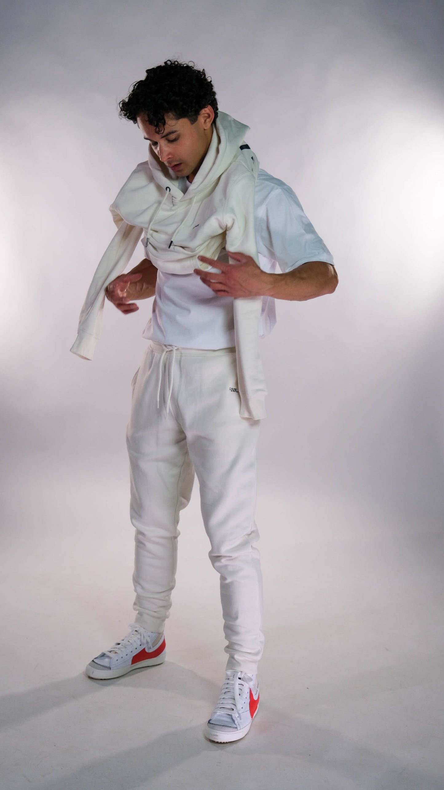 Mannelijk model die zijn ivory hoodie aantrekt. Hij draagt ook de ivory jogger.