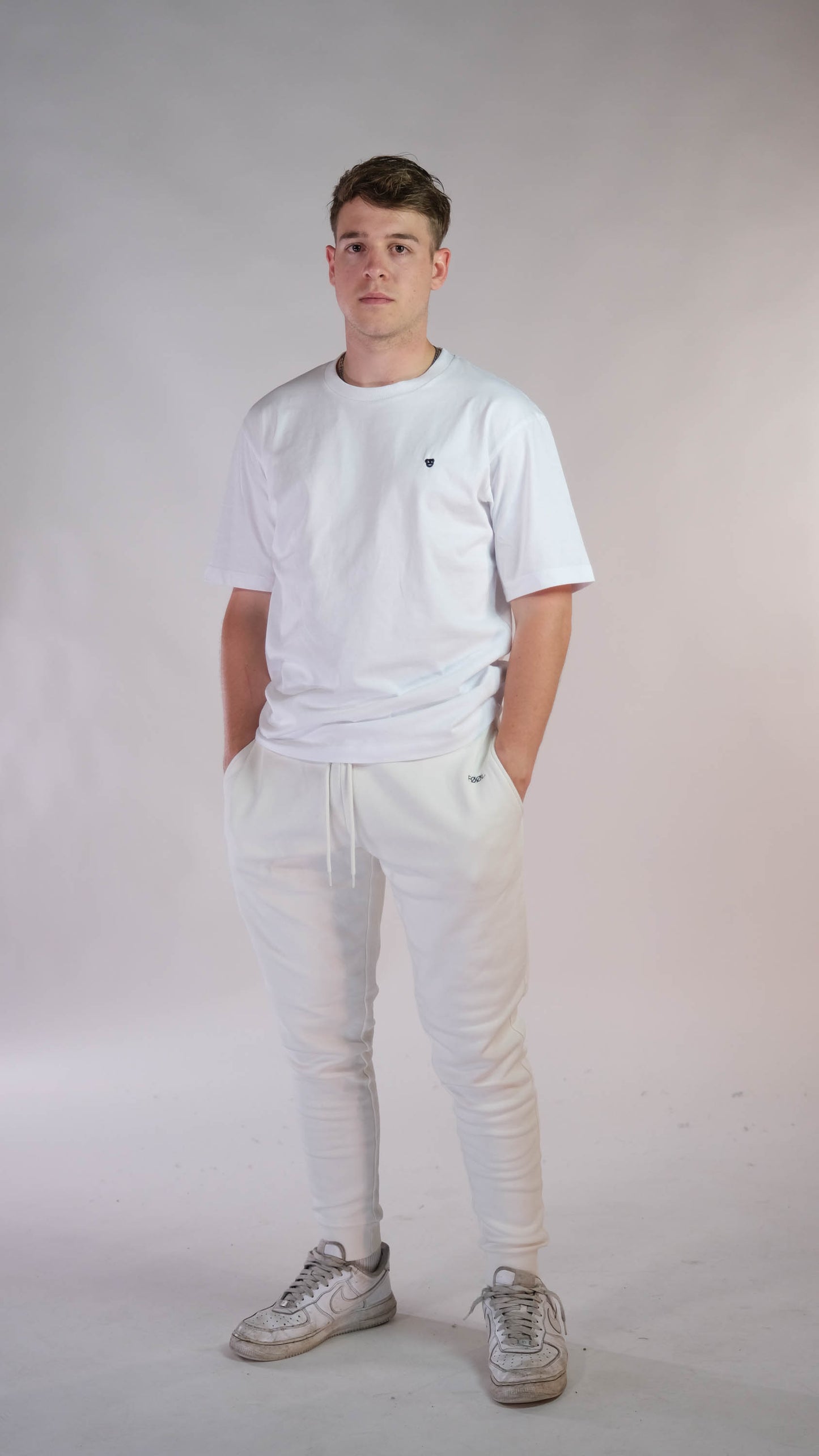 Mannelijk model met wit t-shirt met het 'BEAR' logo. Model draagt de ivory jogger.