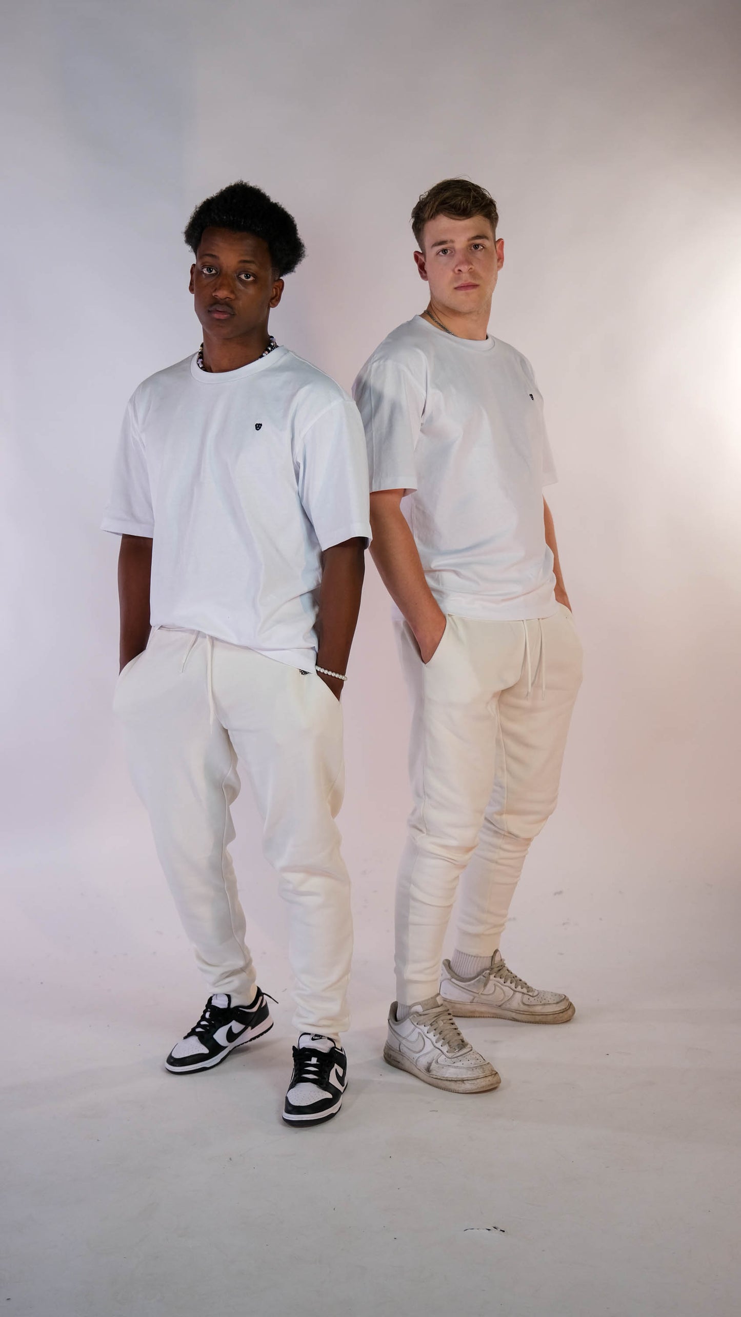 2 mannelijke modellen. Beide met een wit t-shit met zwart 'BEAR' logo en een ivory jogger.