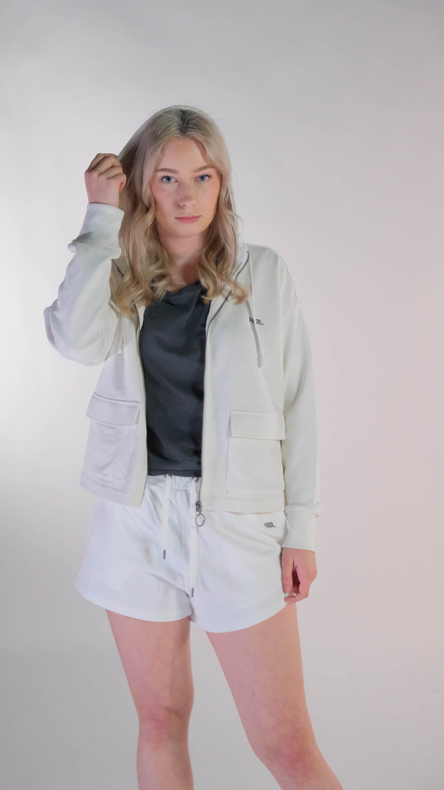 Vrouwelijk model die met het oversized cropped vest, in de kleur ivory, open naar de camera toe staat.