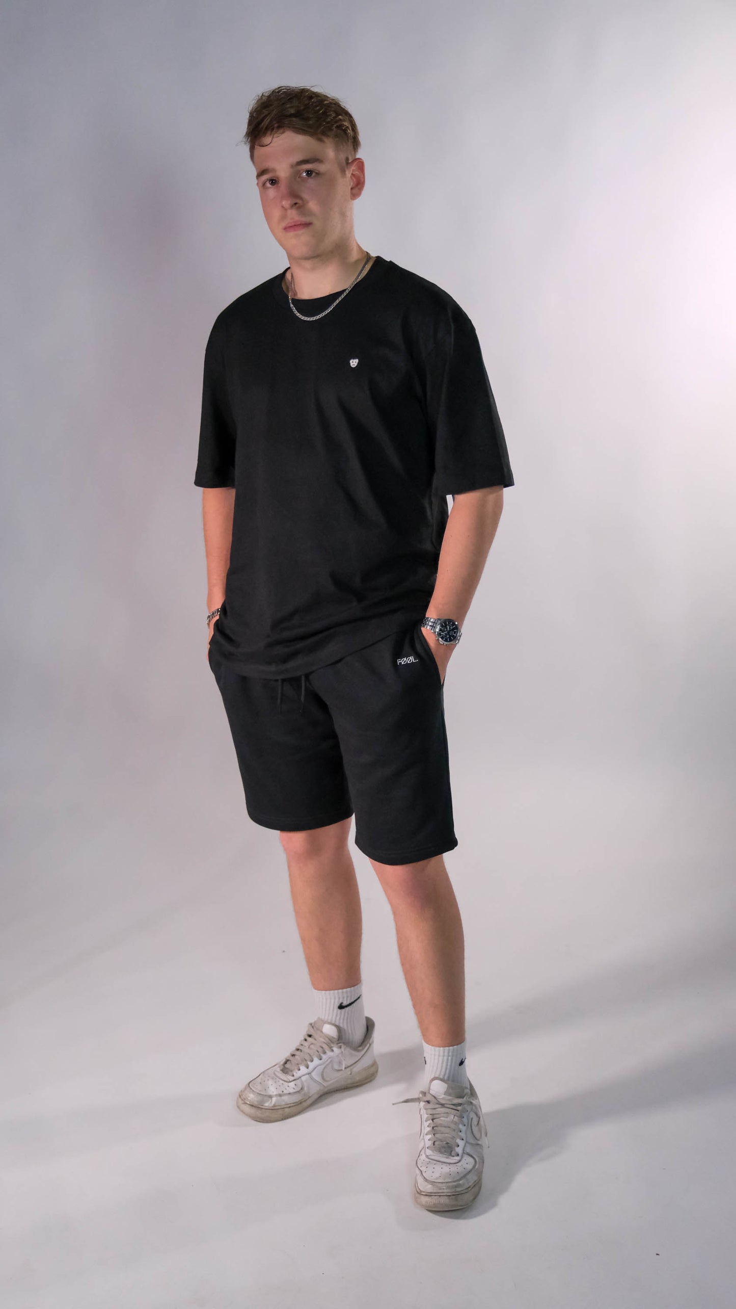 Mannelijk model met een zwart t-shirt met het witte 'BEAR' logo op de borst. Hij draagt de zwarte shorts.