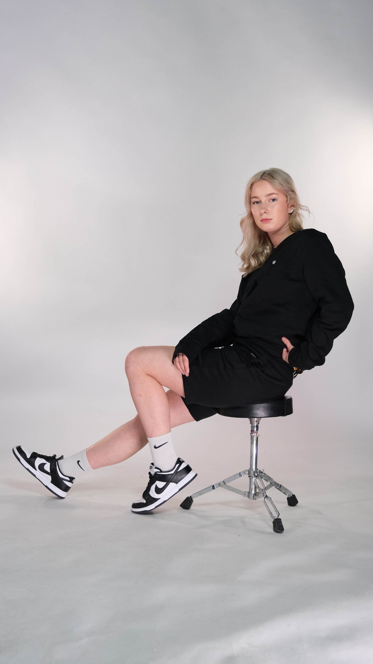 Vrouwelijk model met een zwart t-shirt met het witte 'BEAR' logo op de borst. Hij draagt de zwarte shorts.