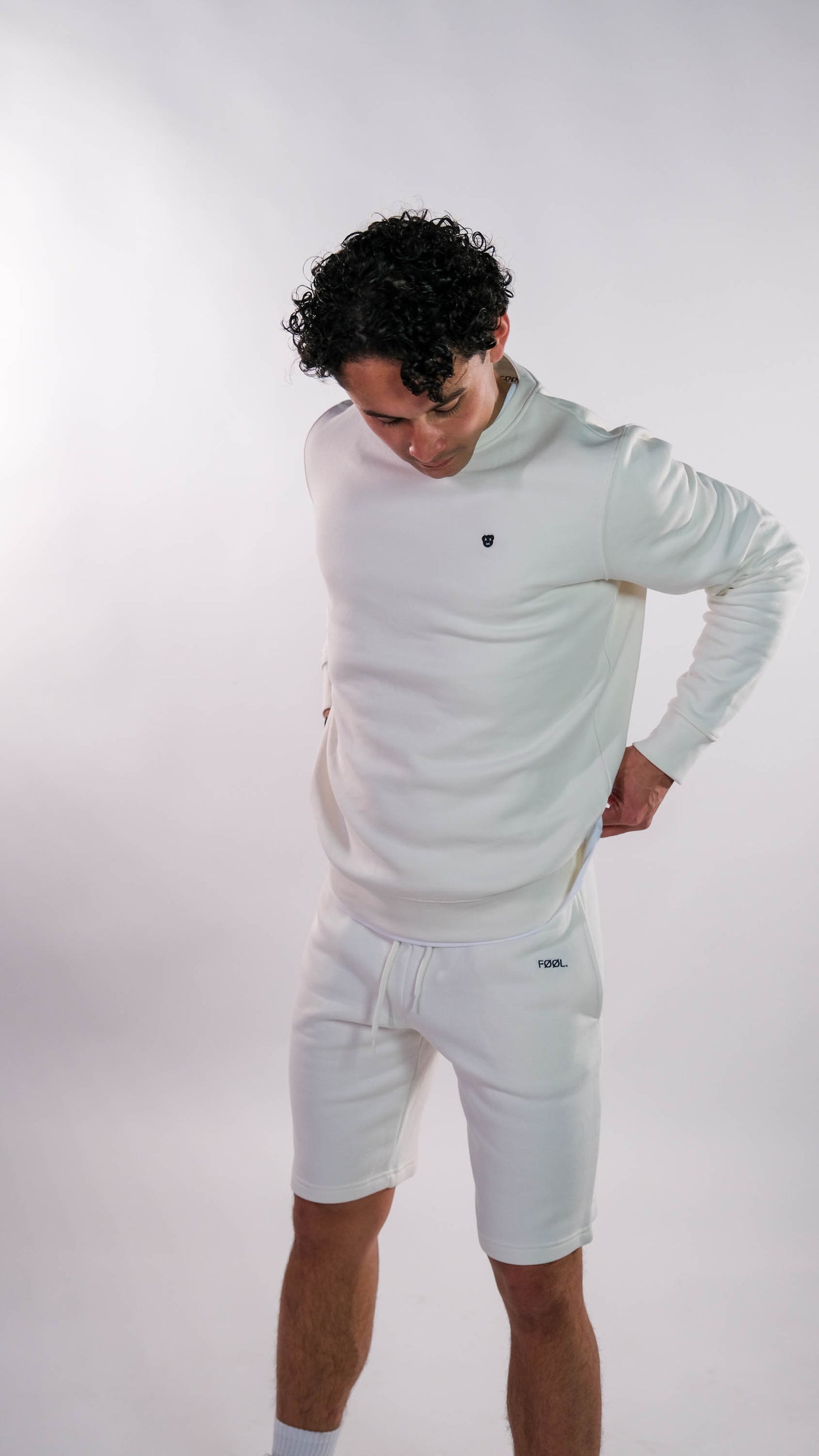 Mannelijk model, hij draagt de ivory sweater met het zwarte 'BEAR' logo op de borst.