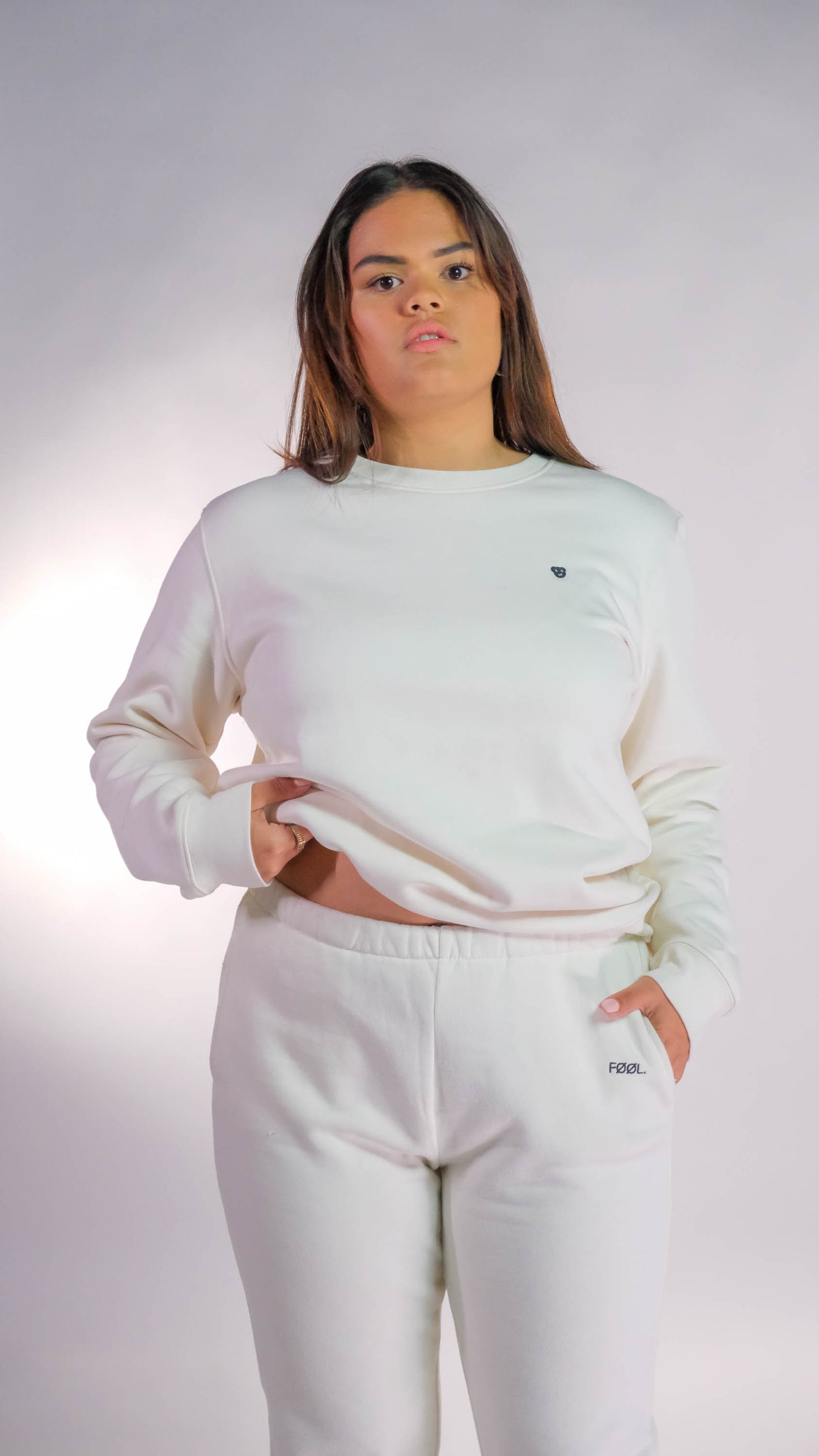 Vrouwelijk model die de ivory swarter draagt met het zwarte 'BEAR' logo op de borst. Ook draagt zij de ivory jogger.