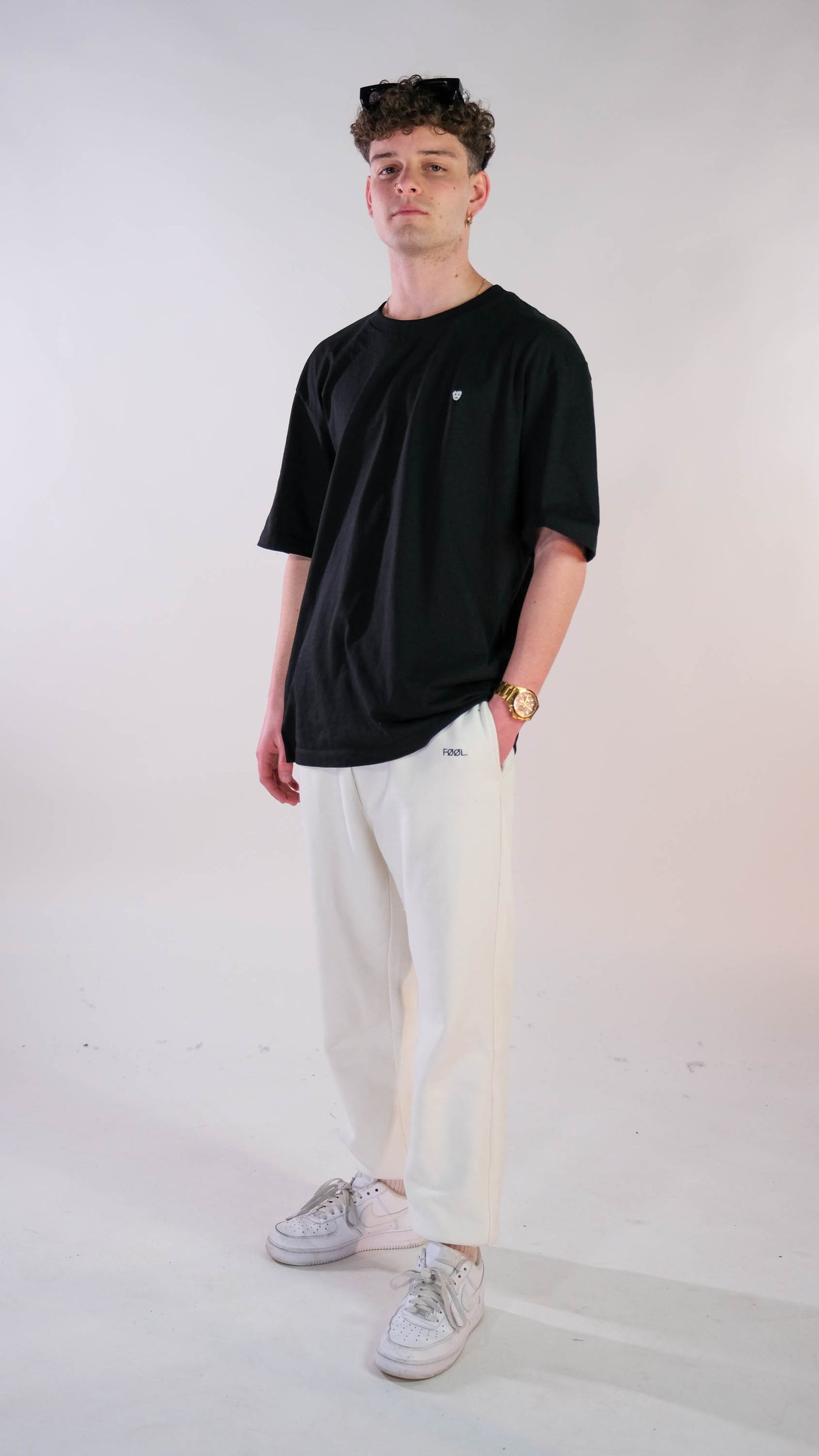 Mannelijk model met zwart t-shirt met wit 'BEAR' logo op de borst. Ook draagt hij de witte 'FØØL' jogger.